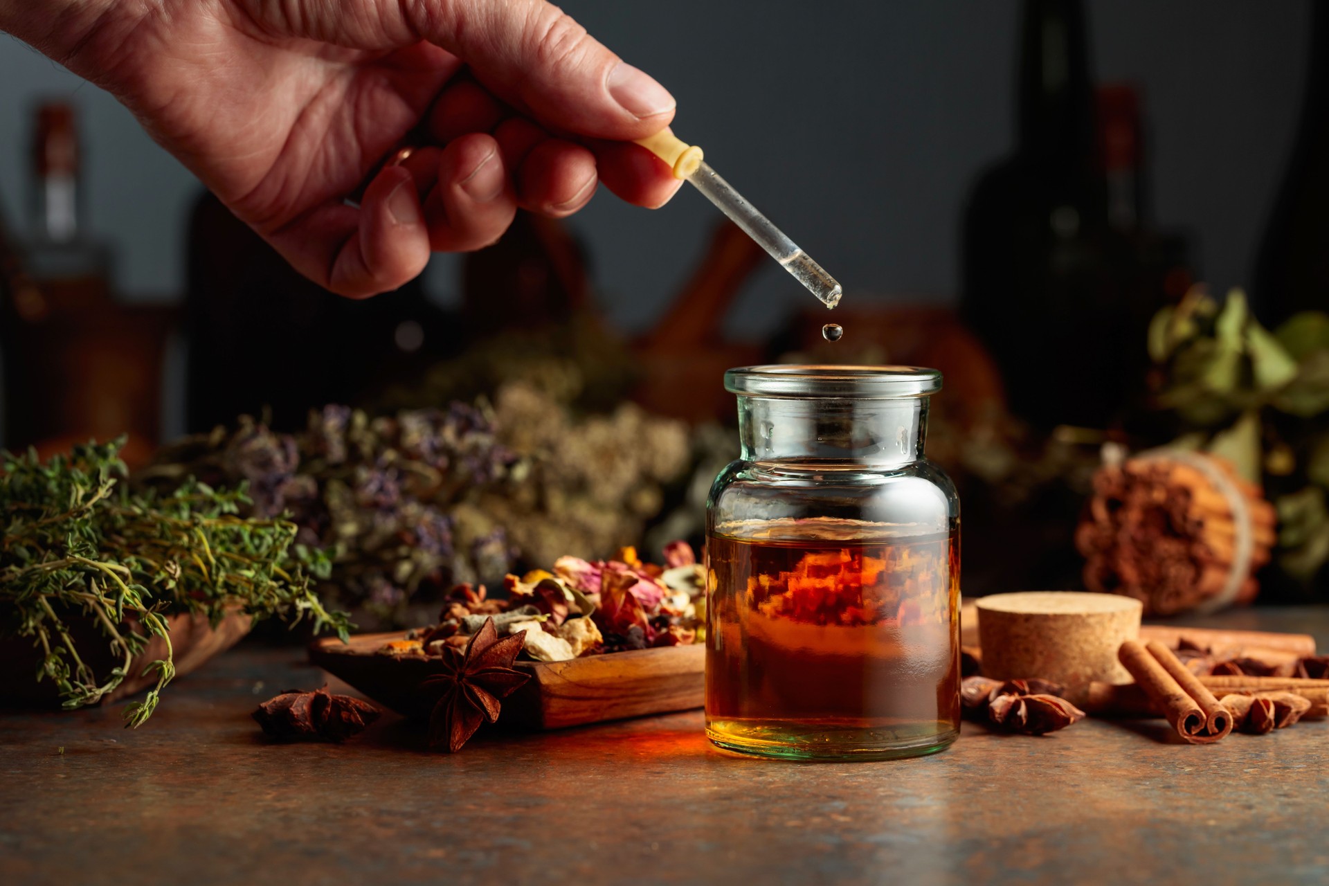 Dropping essential herbal tincture into a small glass bottle.